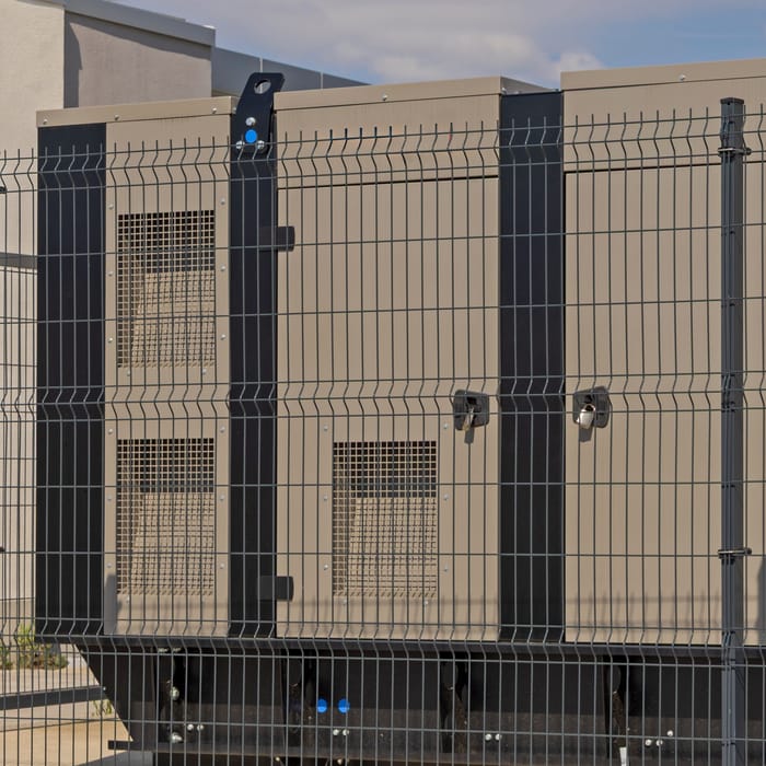 Generator set in a sound-proof enclosure behind a fence