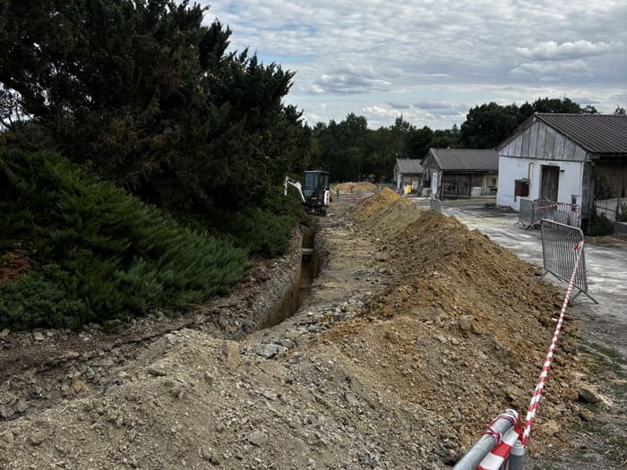 Trench for the cable route running across the farm, excavator in the background