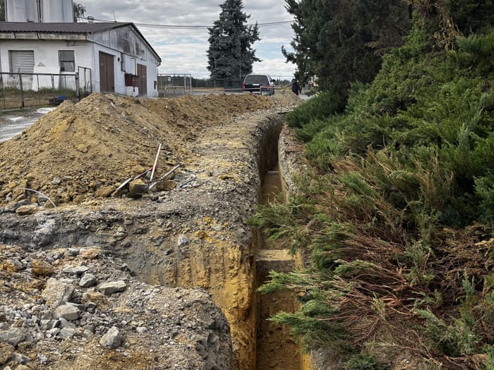 Deep trench cut through rocky ground alongside the building