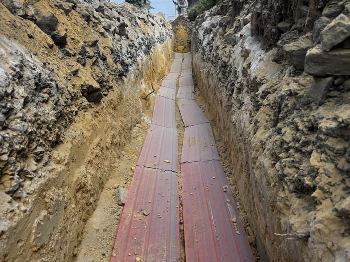 Two rows of red cable protection plates over the cables at the bottom of the trench