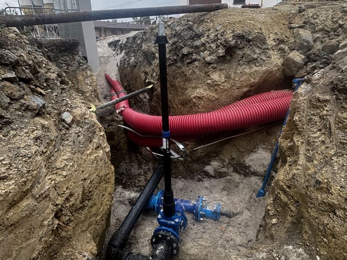 Water main valve with a surface box, cable duct crossing above it